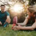 Man and woman stretching together in a park during sunset, promoting physical and mental well-being.