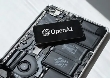 Smartphone displaying OpenAI logo placed on an open laptop motherboard representing GPT-4o update rollback and AI technology.