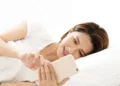 Young woman indulging in social media on smartphone while lying in bed — symbolizing digital overuse.